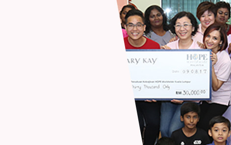 Group of people holding a large check representing Mary Kay’s positive community impact. 