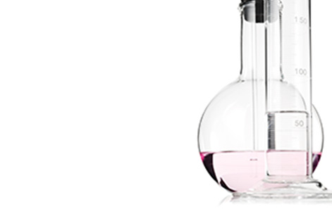 Scientific glassware holding light pink liquid against a white background. 