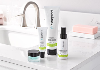 A picture of the three piece Clear Proof® Acne System in white bottles and tubes and Indulge® Soothing Eye Gel in a frosted, translucent pot on a white bathroom counter