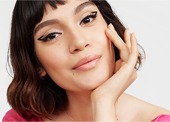 A fair skinned model with a short, playful bob wearing a graphic eyeliner look