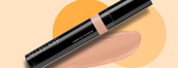 Mary Kay Undereye Corrector and product rub in front of two orange circles