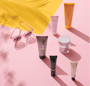 Зображення різних засобів «Мері Кей» для догляду за обличчям та тілом із SPF на рожево-жовтому фоні з сонцезахисними окулярами