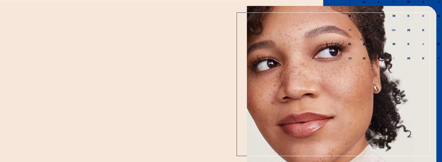 Young woman with freckles and pulled back curly hair slightly smiling and looking off to the side over a light blue and dark blue layered background