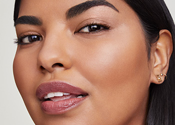 Молода жінка з прямим темним волоссям дивиться в камеру зі злегка відкритою усмішкою та мерехтінням в очах