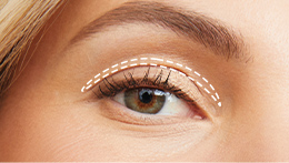 White blonde model with 60s styled hair and cut crease eye shadow look, looking directly at the camera zoomed in on her eye lid to show cut crease eye style, with white line illustration to show on eye lid crease line.