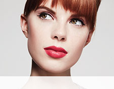 Get the step-by-step application tips for the Sweet Pinks Look created by Mary Kay Guest Makeup Artist Sam Addington. A young red head is seen staring at the top left corner. She is wearing pink eye shadow and red lipstick.