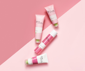 The Botanical Effects skin care set in white and pink tubes on a pink background