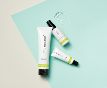 The Clear Proof Acne System in white and green tubes on a teal and gray background