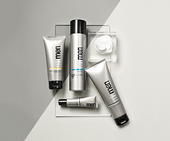 The MKMen Skin Care set in gray tubes on a gray background with a dollop of shave foam