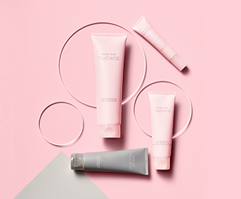 The TimeWise Miracle Set 3D skin care regimen in pink and gray tubes on a pink and gray background