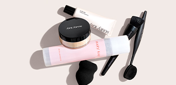 Вирівнювальна основа "Мері Кей" розміщена на мармуровій стільниці у ванній кімнаті поряд із тональним кремом, мінеральною пудрою, пензлем для макіяжу та сукулентом.