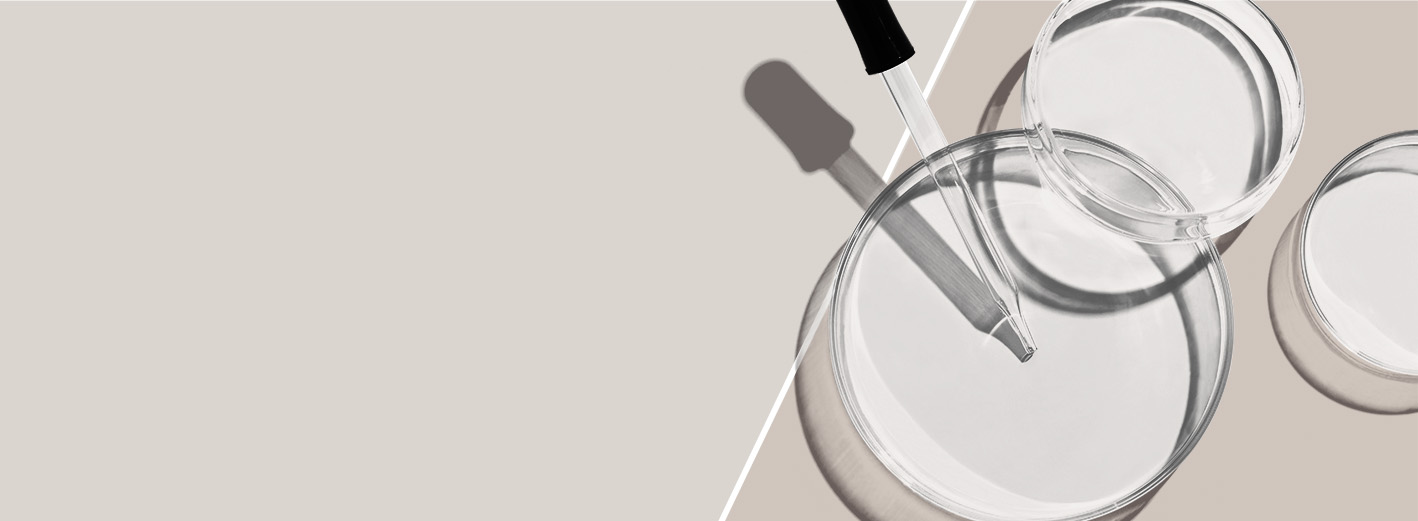 A trio of empty petri dishes with a dropper over a neutral two-toned background