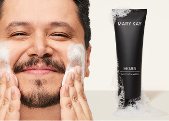 A dark-haired man with facial hair happily washing his face pictured next to MKMen Daily Facial Wash