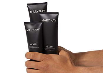 The MKMen skin care regimen held in the hands of a man as if he’s grabbing for the products
