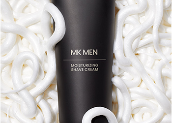 MKMen Moisturizing Shave Cream surrounded by a playful shave cream product rub