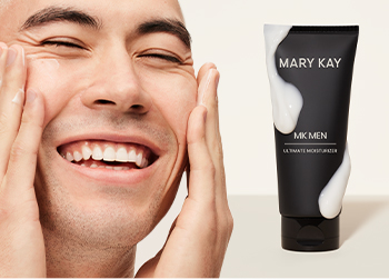 A young, dark-haired man happily moisturizing his skin pictured next to MKMen Ultimate Moisturizer