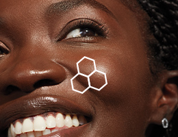 Up close macro image of a smiling black woman with brown eyes with an outline of the TimeWise 3D Complex on her cheek