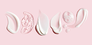 Мазки  різних засобів для догляду за шкірою Mary Kay на білому тлі.